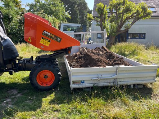 Camion à benne transportant de la terre sur un terrain verdoyant.