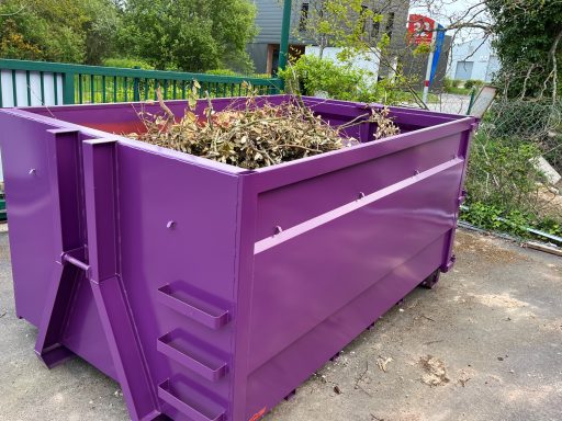 Container de déchets de couleur violette rempli de débris végétaux.